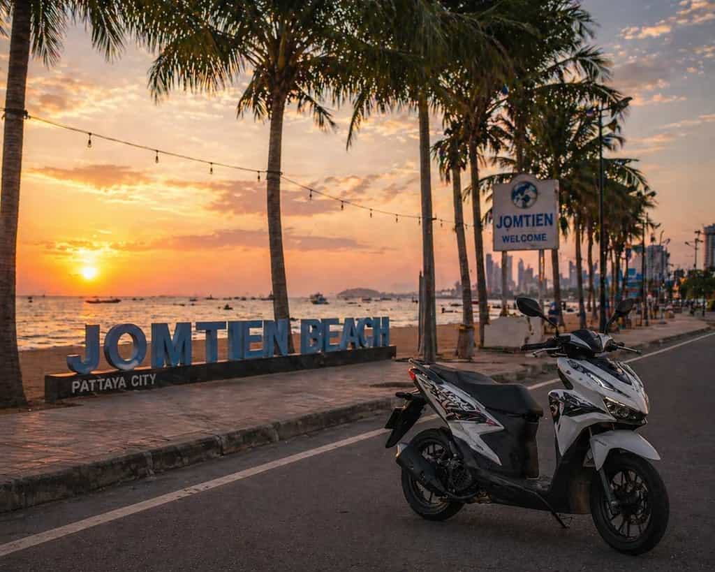 Honda scooter at the Jomtien Beach sunset sign in Pattaya, Thailand: Byklo scooter rental