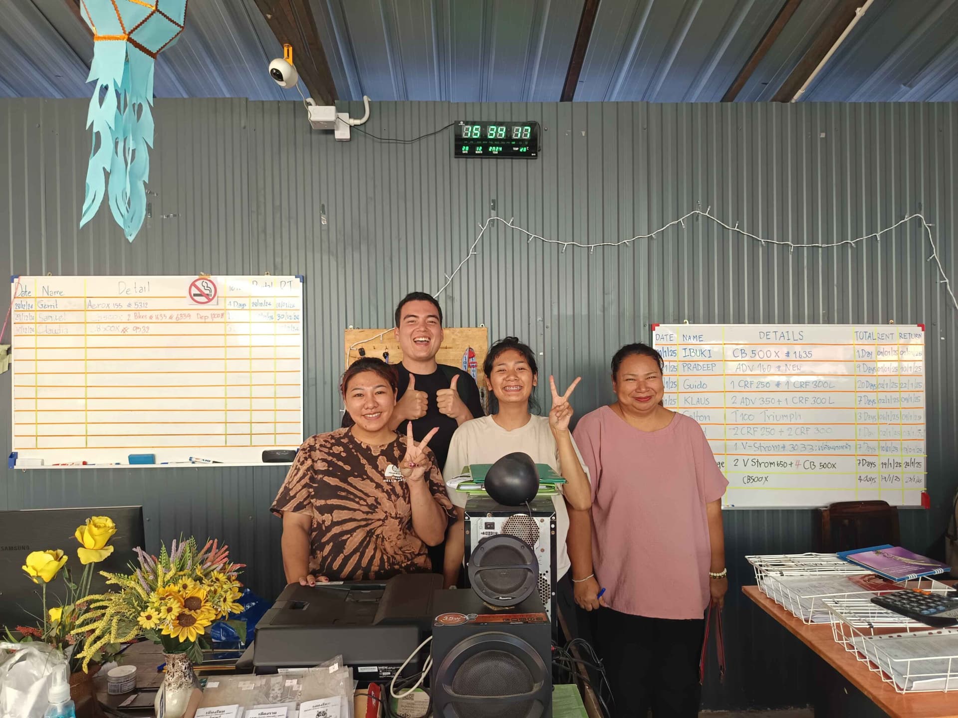 People at motorbike rental shop smiling and doing the peace sign