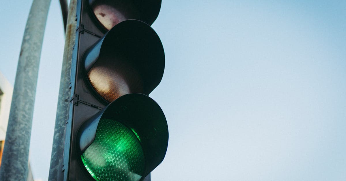 Close-up of a green traffic light against a clear blue sky, symbolizing go and safety.