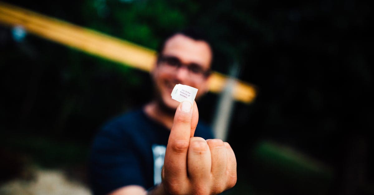 Portrait of a man smiling and holding a SIM card outdoors with focus on the hand.